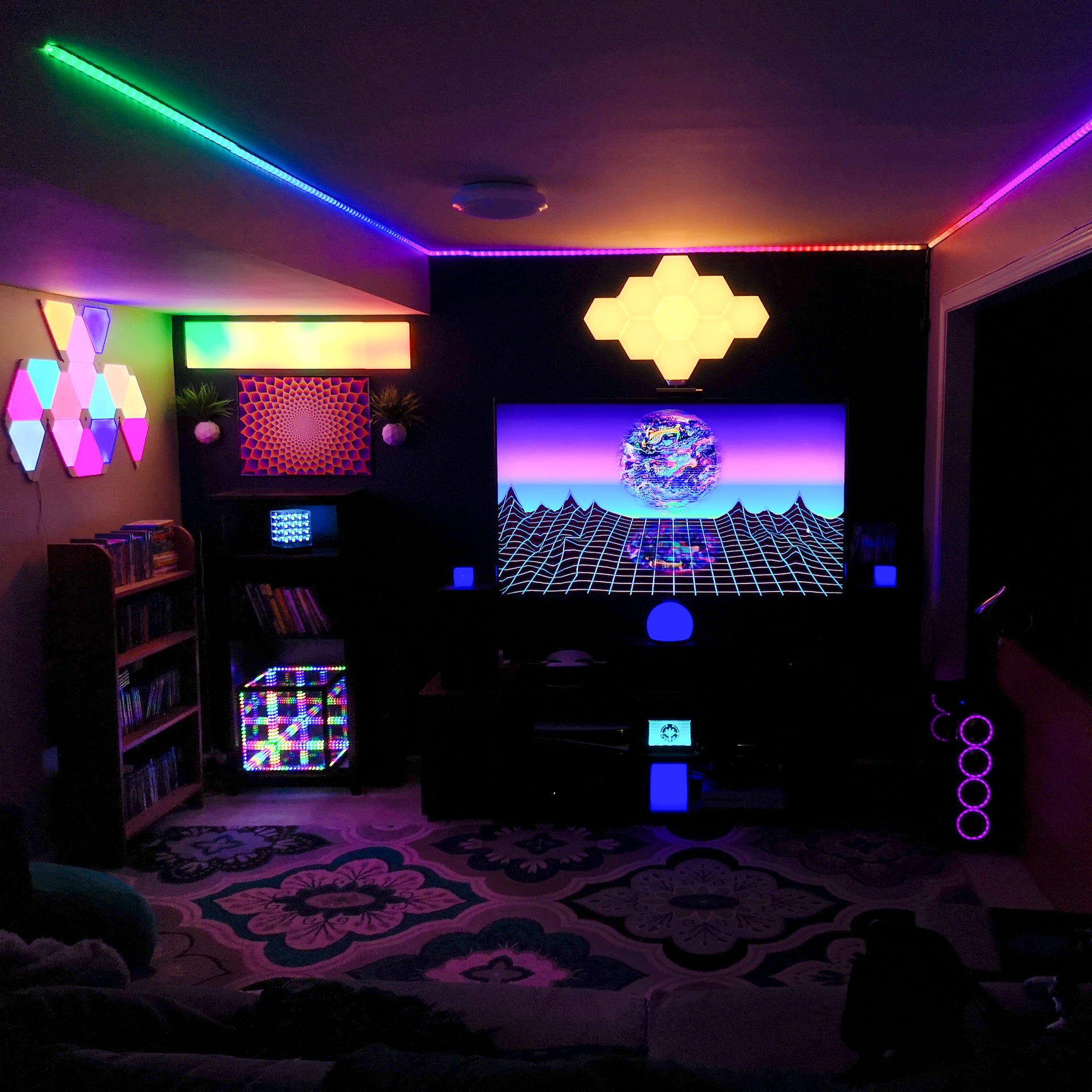 Room with a TV in the middle of the wall facing viewer, a small patterned rug on the floor, LED strip lights lining the ceiling, a HyperCube, and other creative decorative lighting ideas