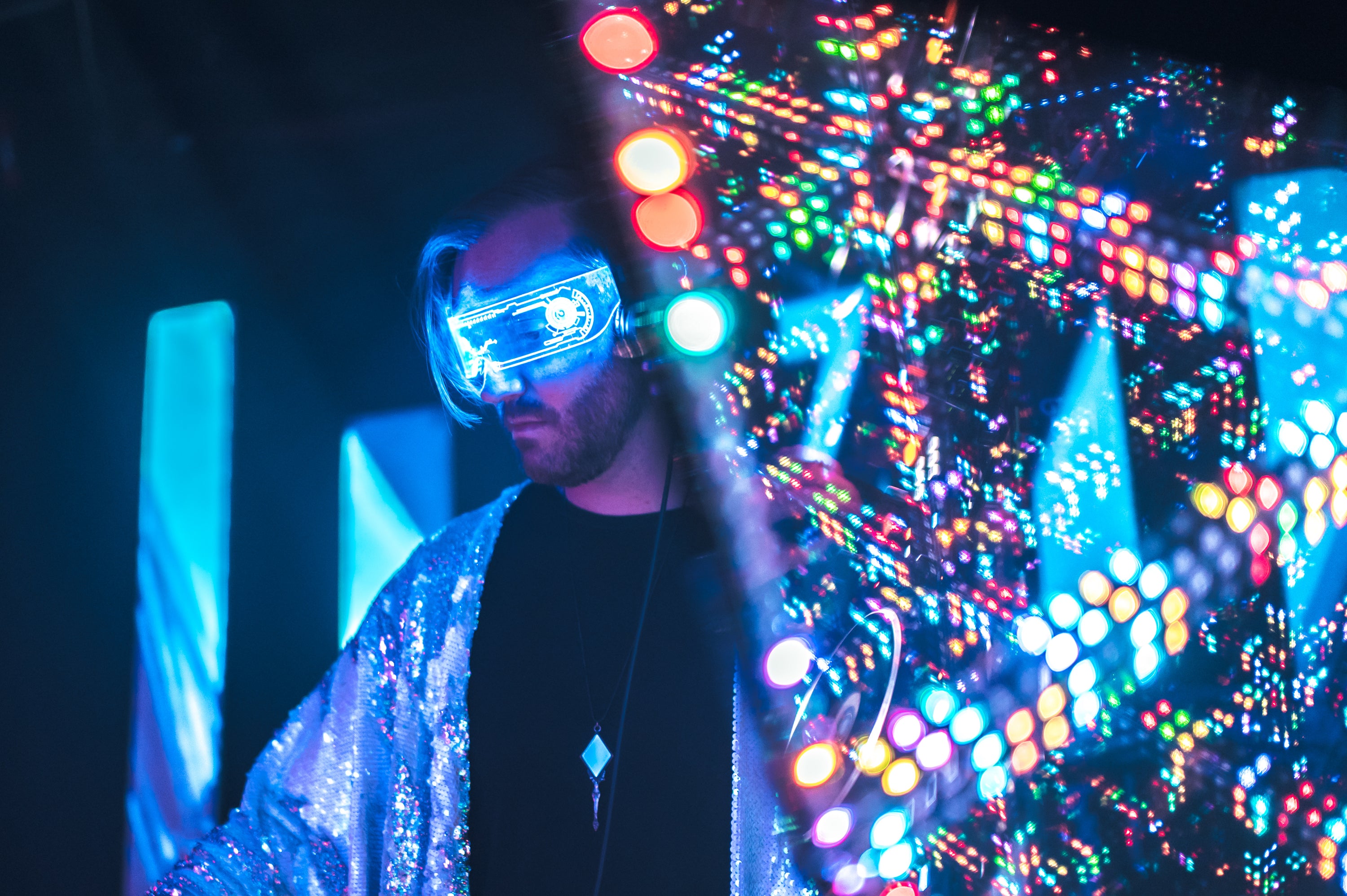 DJ performing set at festival, captivating audience with sound-reactive color changing lights