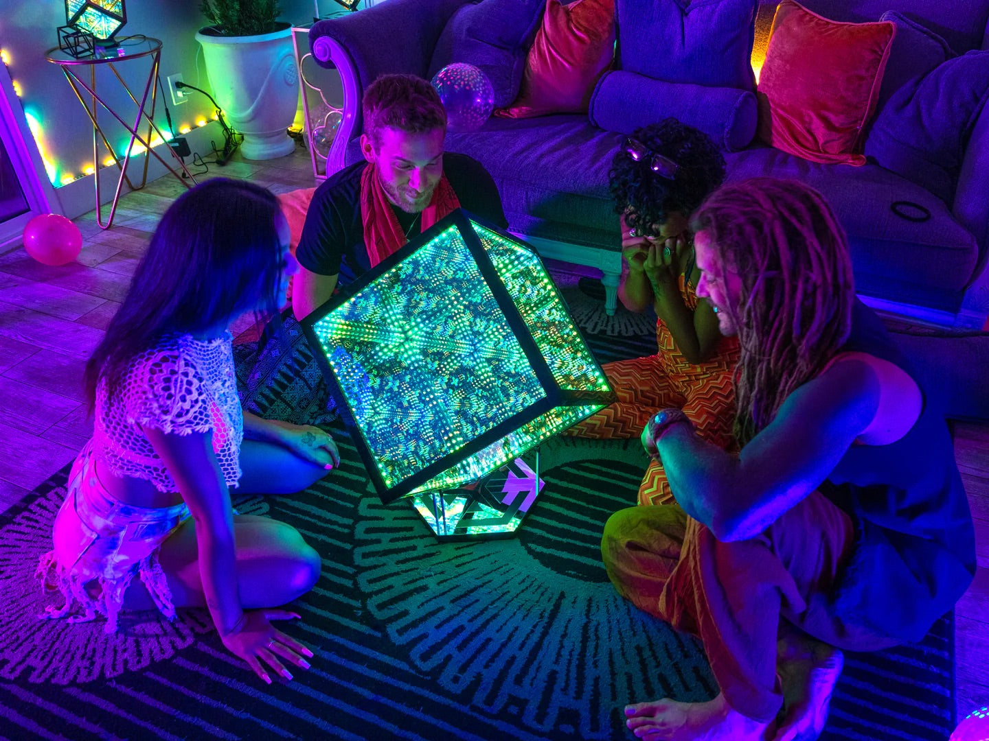 Four persons sitting in a circle around a Hypercube with multicolored LED lights in the living room
